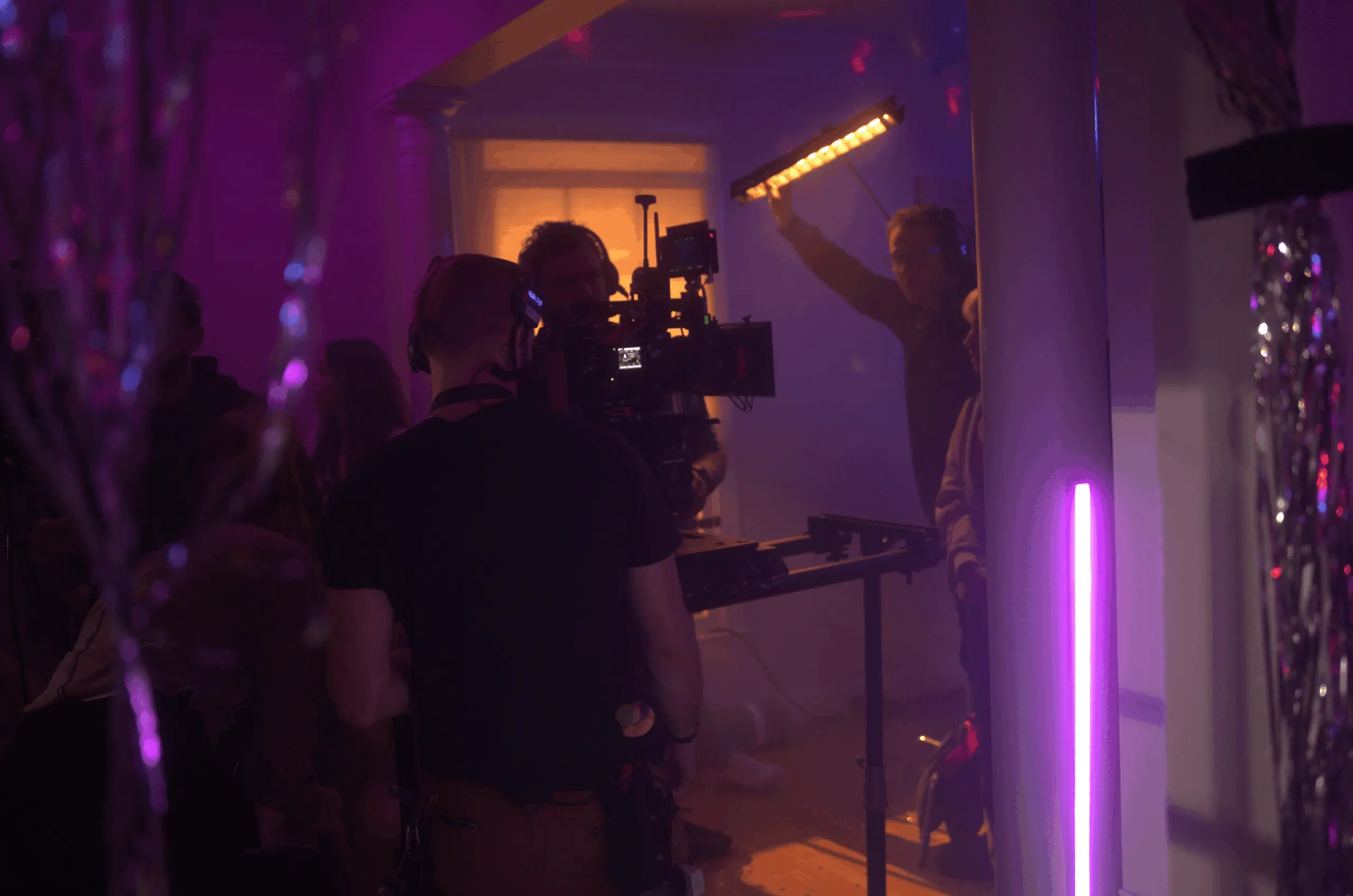Camera crew filming under stylized practical lighting